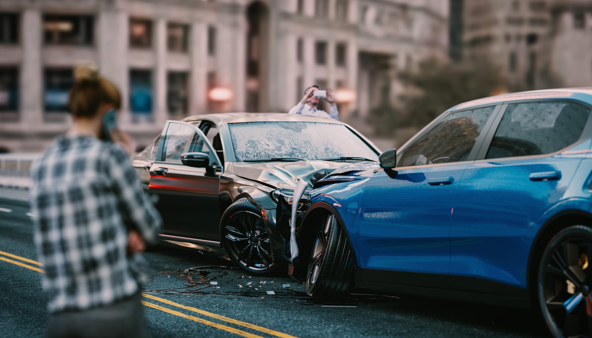 The aftermath of a car accident on a city street. A male driver is documenting the scene with his phone while the blurred out woman driver is on her phone.
