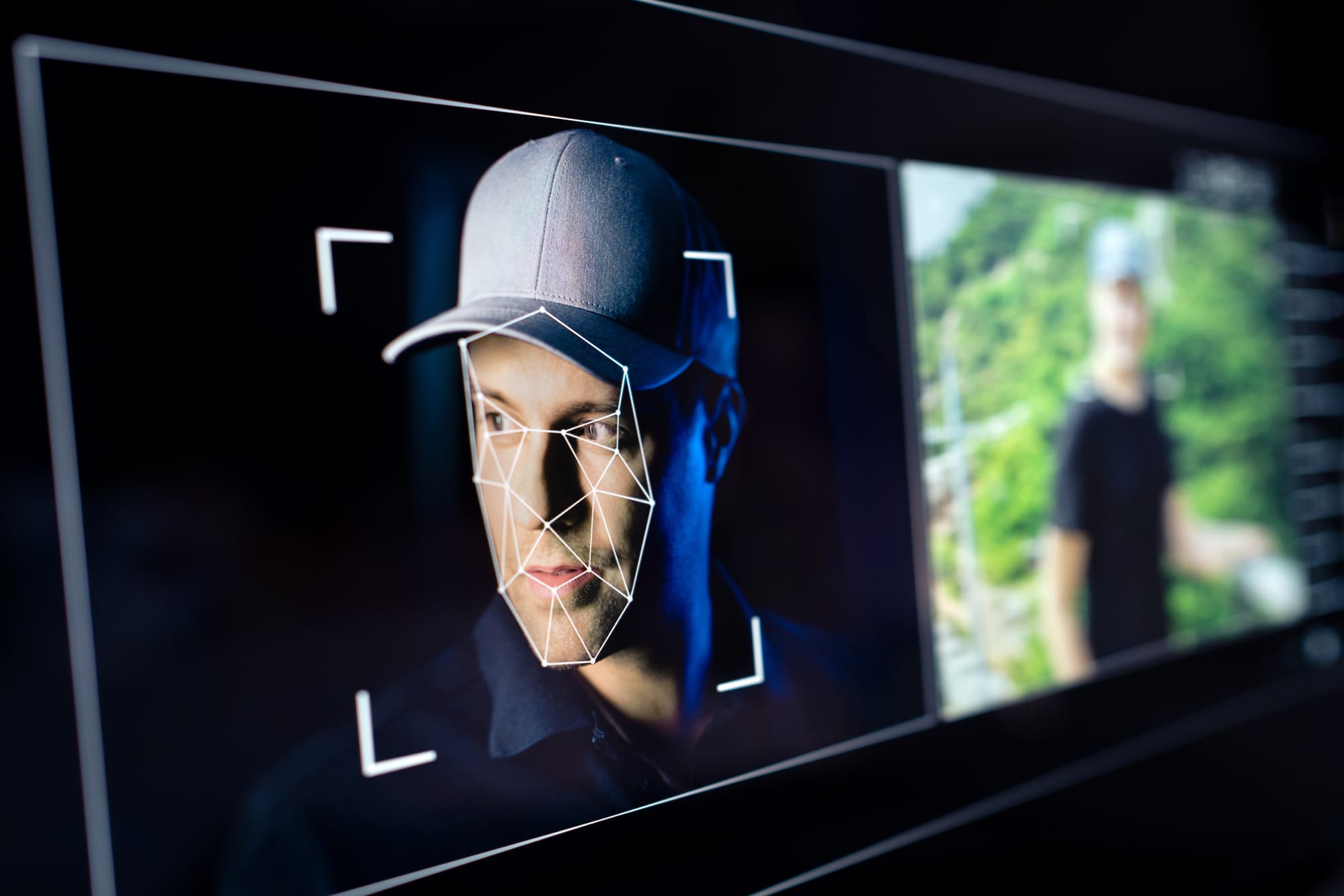Digital facial recognition technology illustrating AI deepfakes and online impersonation of a man in a white baseball cap next to a blurred real image.