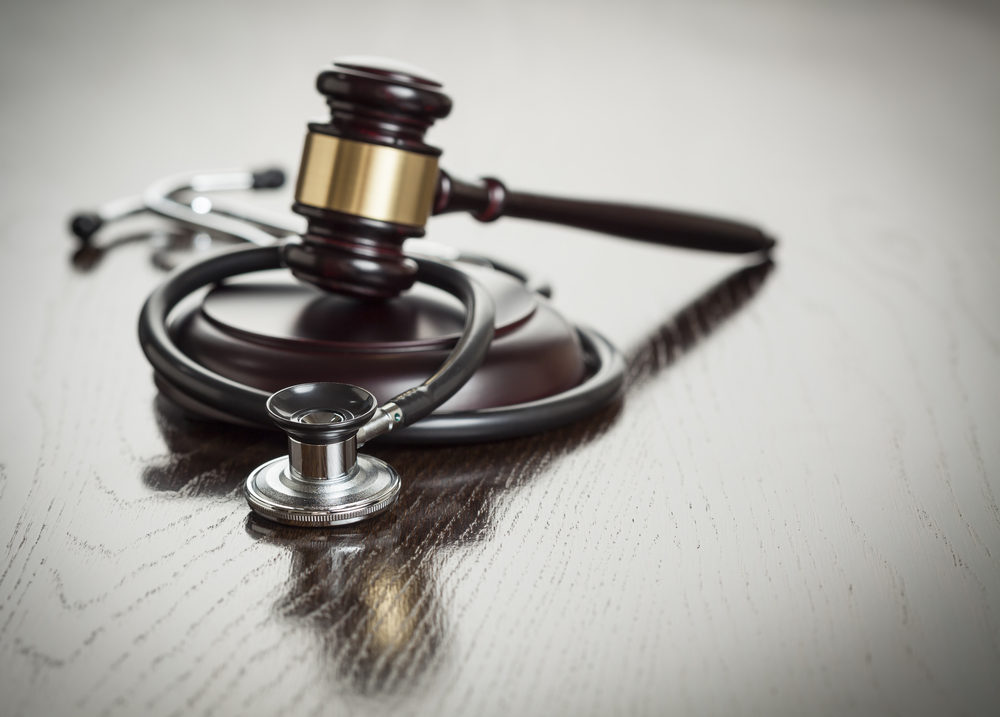 Gavel and Stethoscope on Reflective, Wooden Table